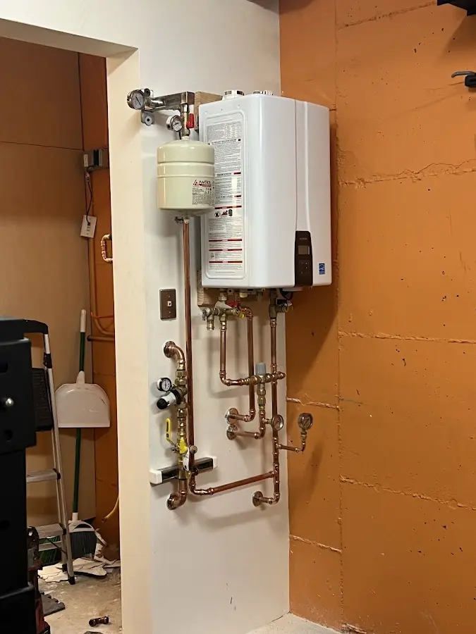 Plumbing technician inspecting water heater connections in Delphos